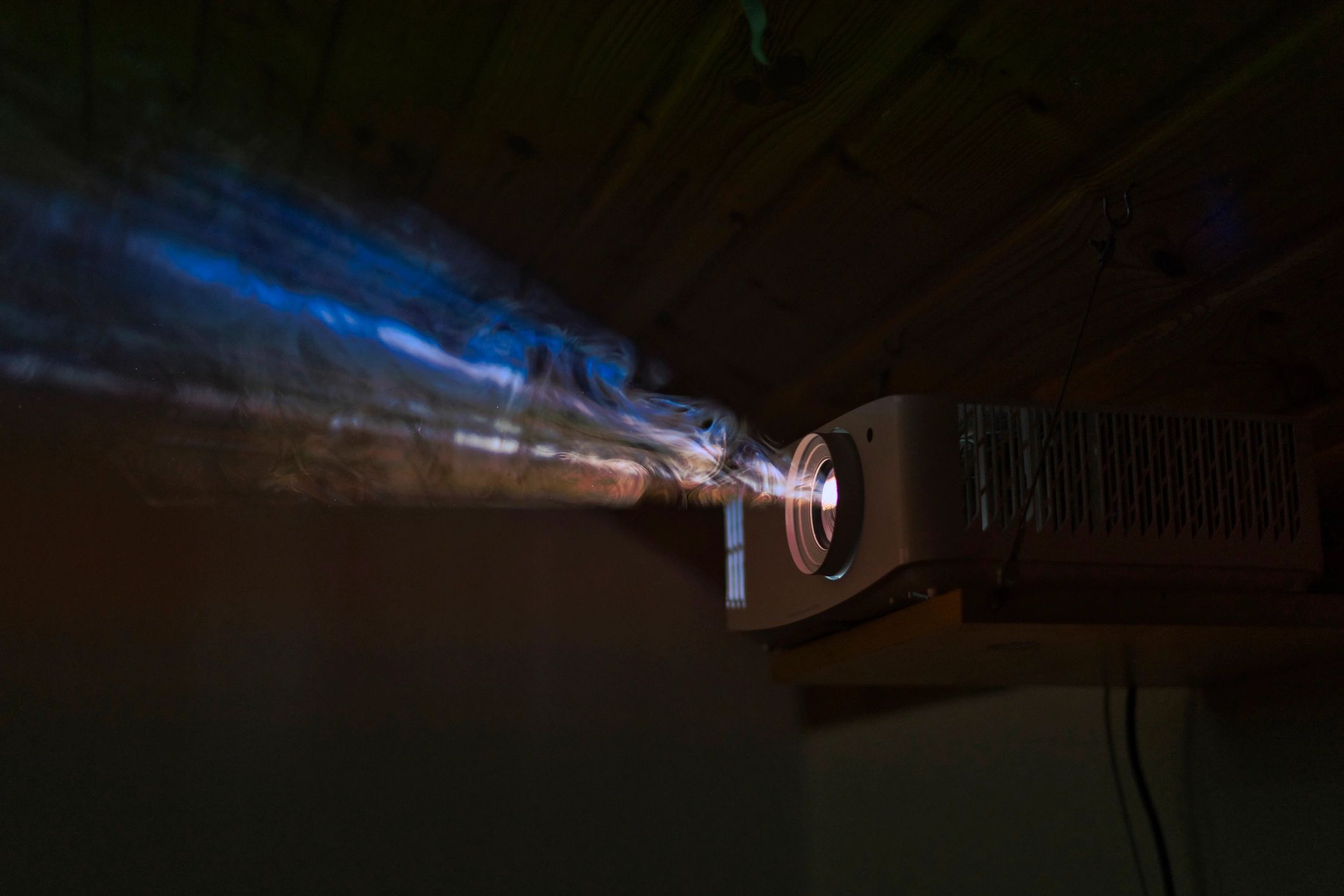 Projector beam in a dark room representing projector home theater installation